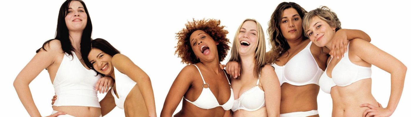 Racially diverse women in white undergarments laughing.